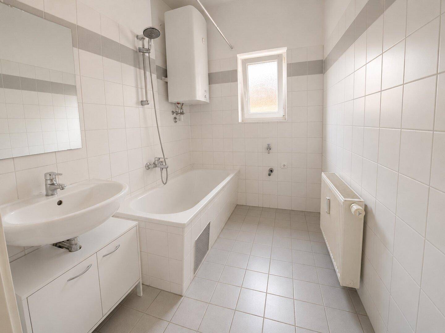 Funktionales Badezimmer mit Badewanne, Waschbecken und Fenster für natürliche Belüftung.