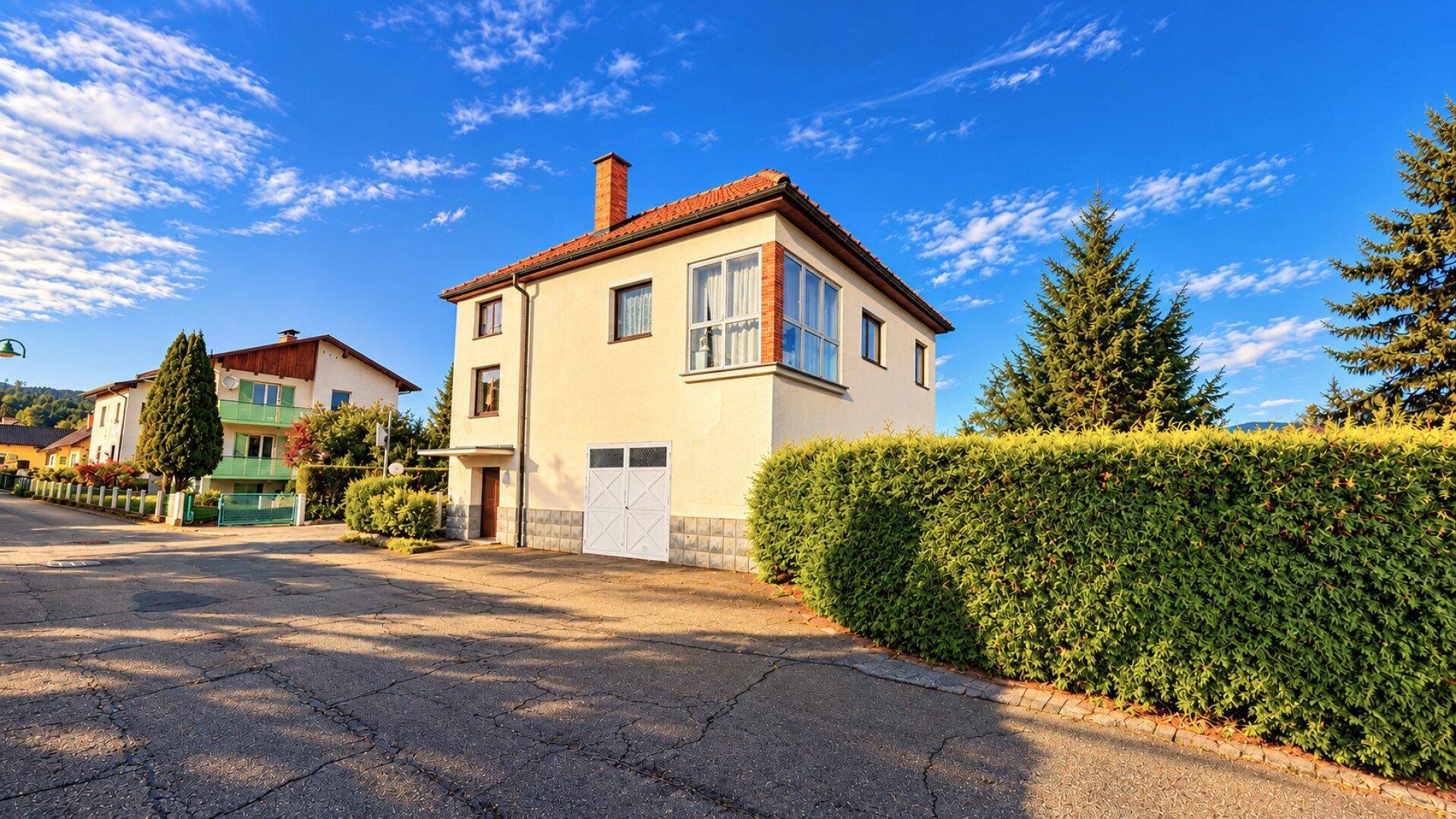 Einfamilienhaus mit Garage und gepflegter Hecke an einer ruhigen Wohnstraße.