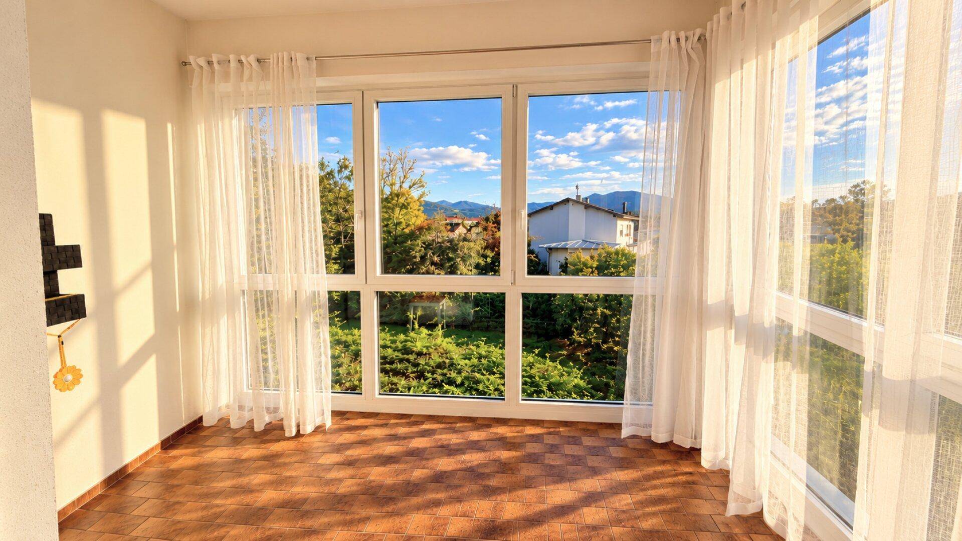 Heller Wintergarten mit großen Fenstern und Blick ins Grüne, ausgestattet mit Fliesenboden.