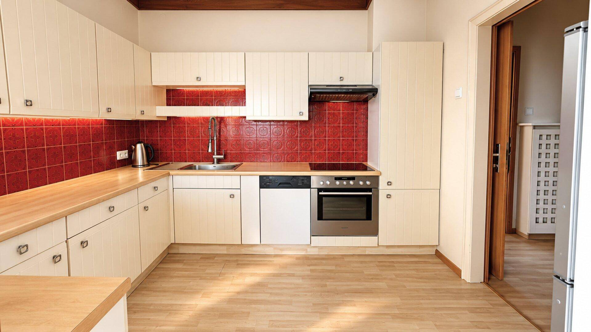 Einbauküche mit hellen Schränken, roten Fliesen und Holz-Arbeitsplatten, ausgestattet mit modernen Geräten.