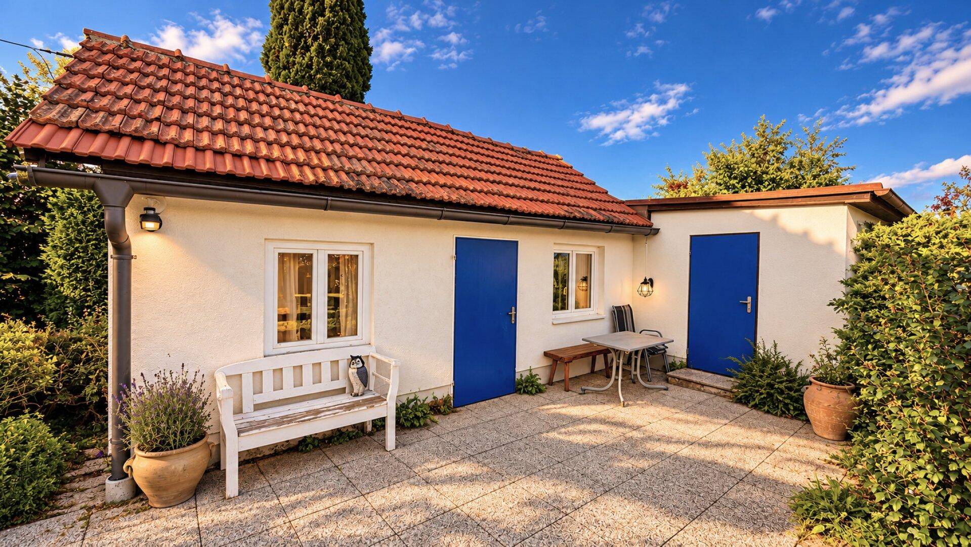 Gemütlicher Außenbereich mit gepflasterter Terrasse, Sitzgelegenheiten und blauen Türen.