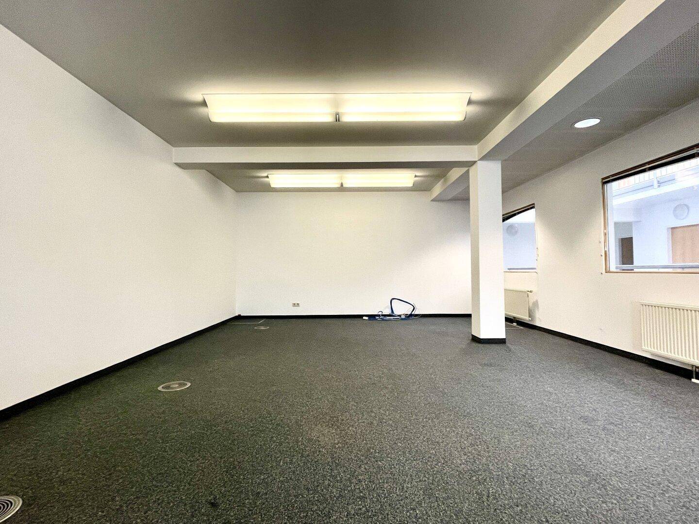 Leeres Büro mit Teppichboden und weißen Wänden, bereit für individuelle Gestaltung.