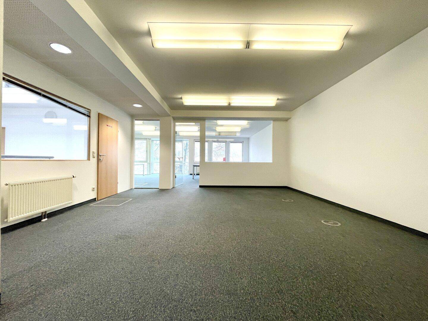 Geräumiges Büro mit Teppichboden und großen Fenstern, das eine flexible Raumgestaltung ermöglicht.