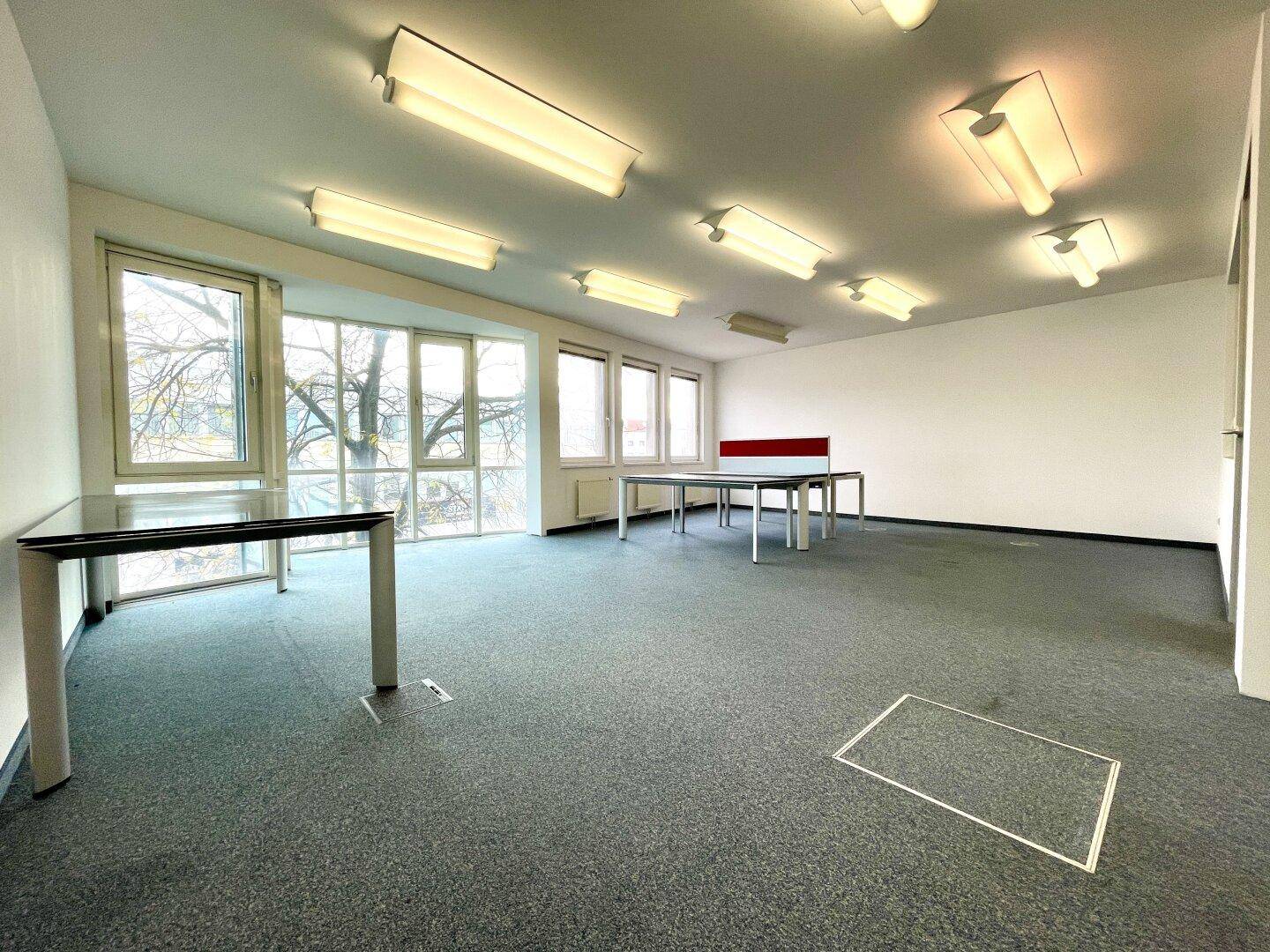 Großes, helles Büro mit Teppichboden, großen Fenstern und flexiblen Arbeitsplatzmöglichkeiten.