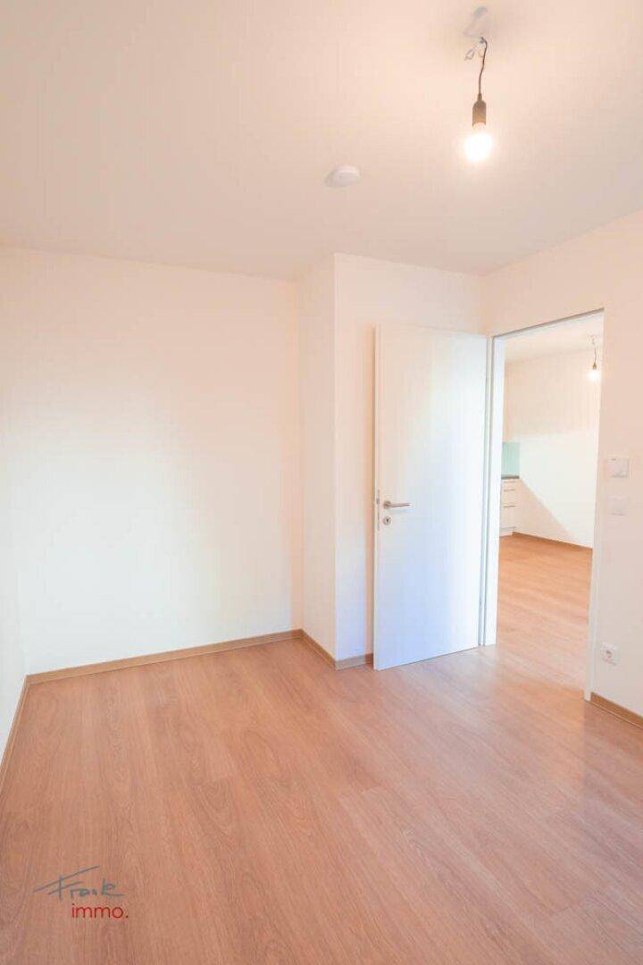Leerer Raum mit Holzboden und weißen Wänden, ideal für individuelle Gestaltung.