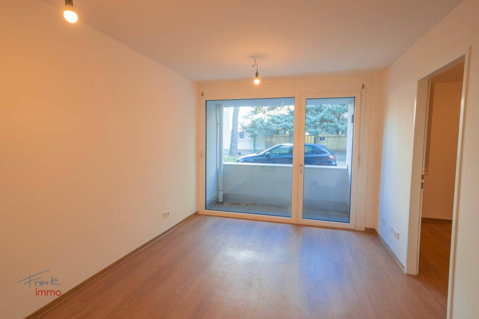 Helles Wohnzimmer mit Zugang zu einem Balkon und schönem Holzboden.