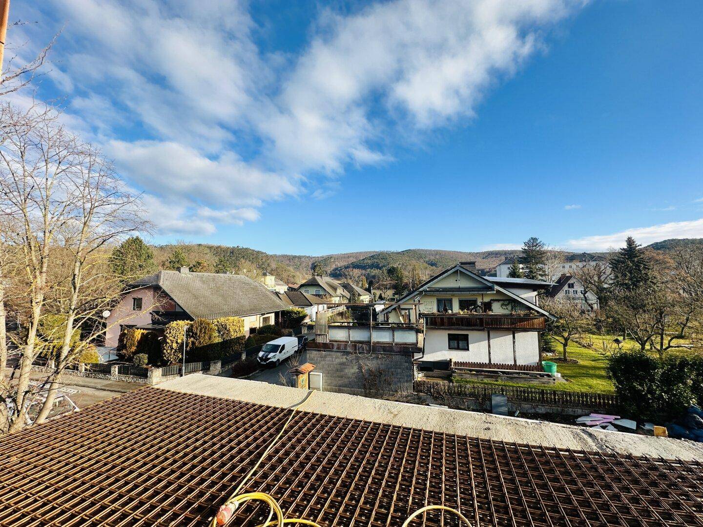 Weitblick über eine Wohnsiedlung mit Häusern und grüner Landschaft unter blauem Himmel.