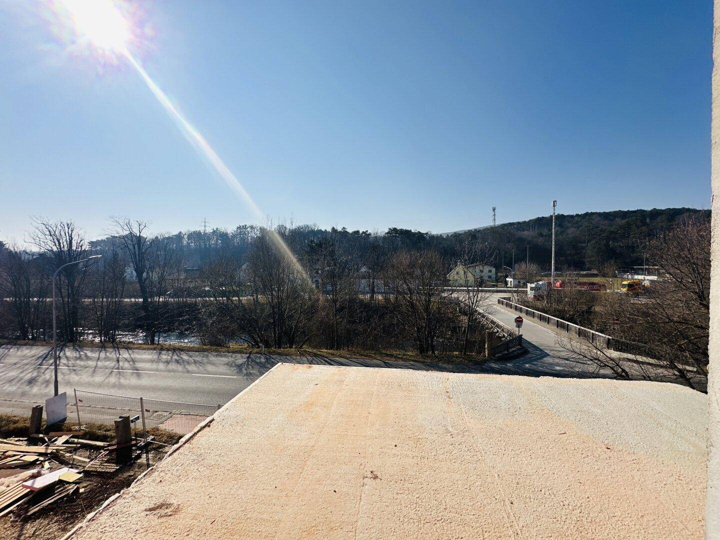 Weitläufiger Blick von einer im Bau befindlichen Terrasse auf eine Straße und die umliegende Landschaft.