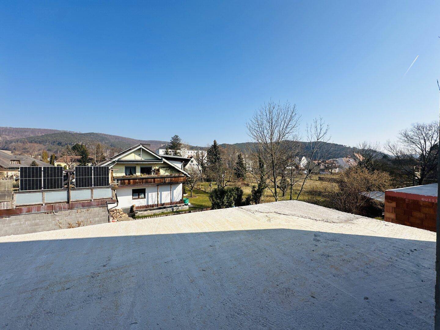 Panoramablick von der oberen Etage auf die umliegende Landschaft und benachbarte Häuser mit Solaranlage.