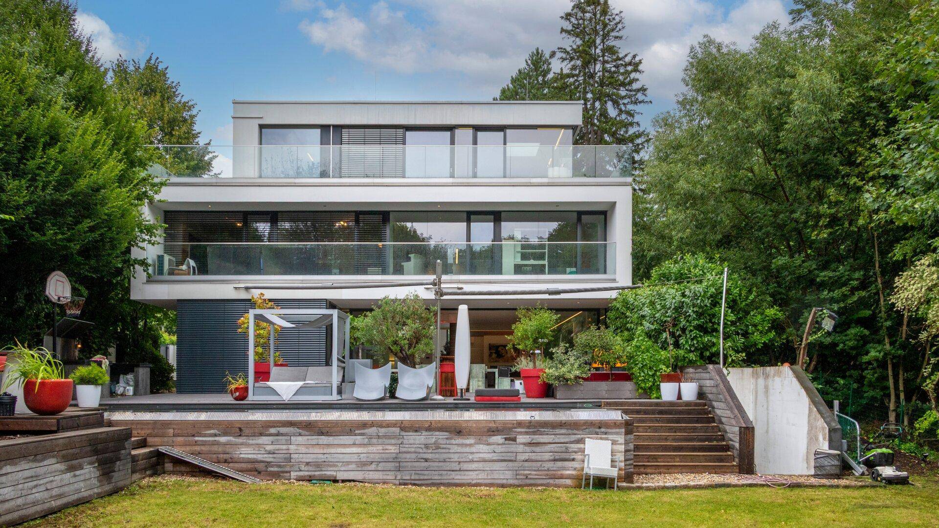 Weitläufiger Gartenbereich mit moderner Villa, Poolterrasse und üppiger Vegetation.