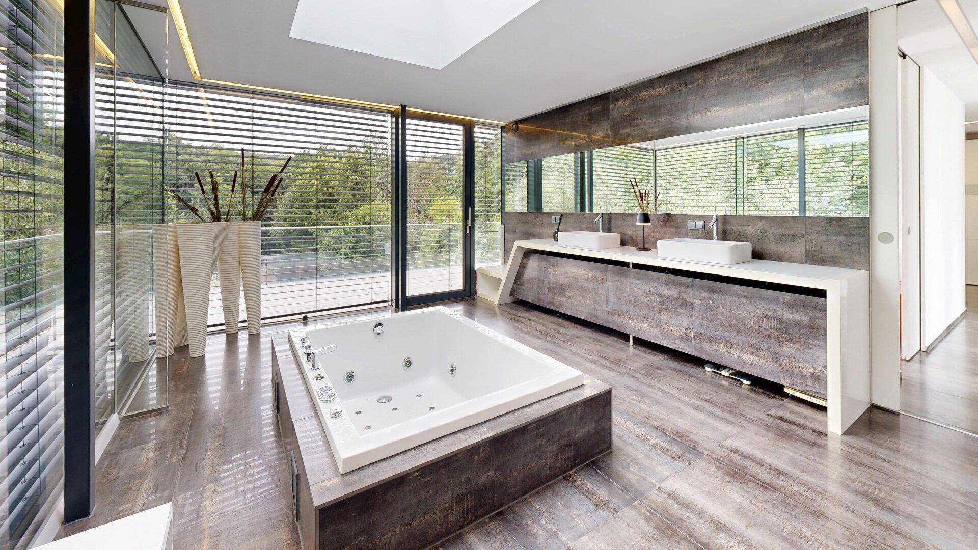 Großzügiges Badezimmer mit moderner Badewanne, Doppelwaschbecken und raumhohen Fenstern.
