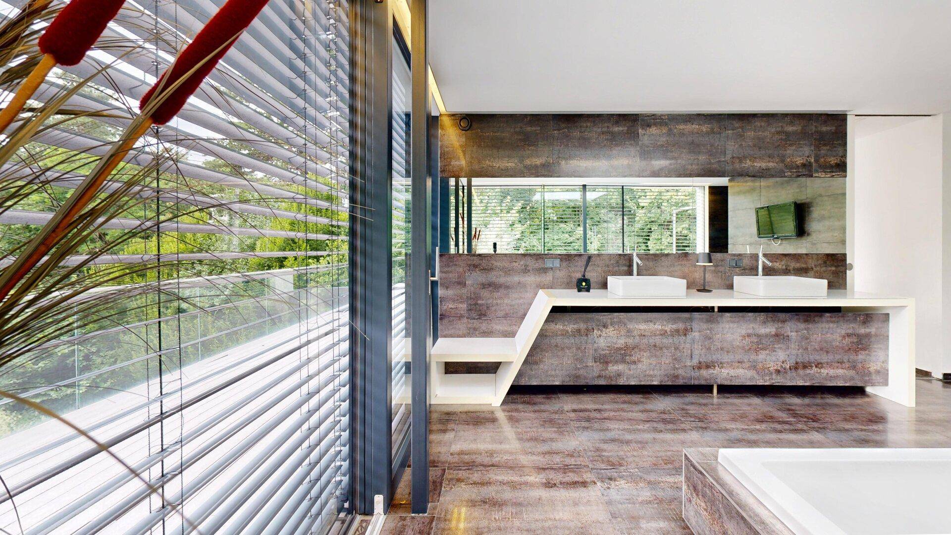 Modernes Badezimmer mit Doppelwaschbecken und großen Fenstern, die viel Tageslicht hereinlassen.