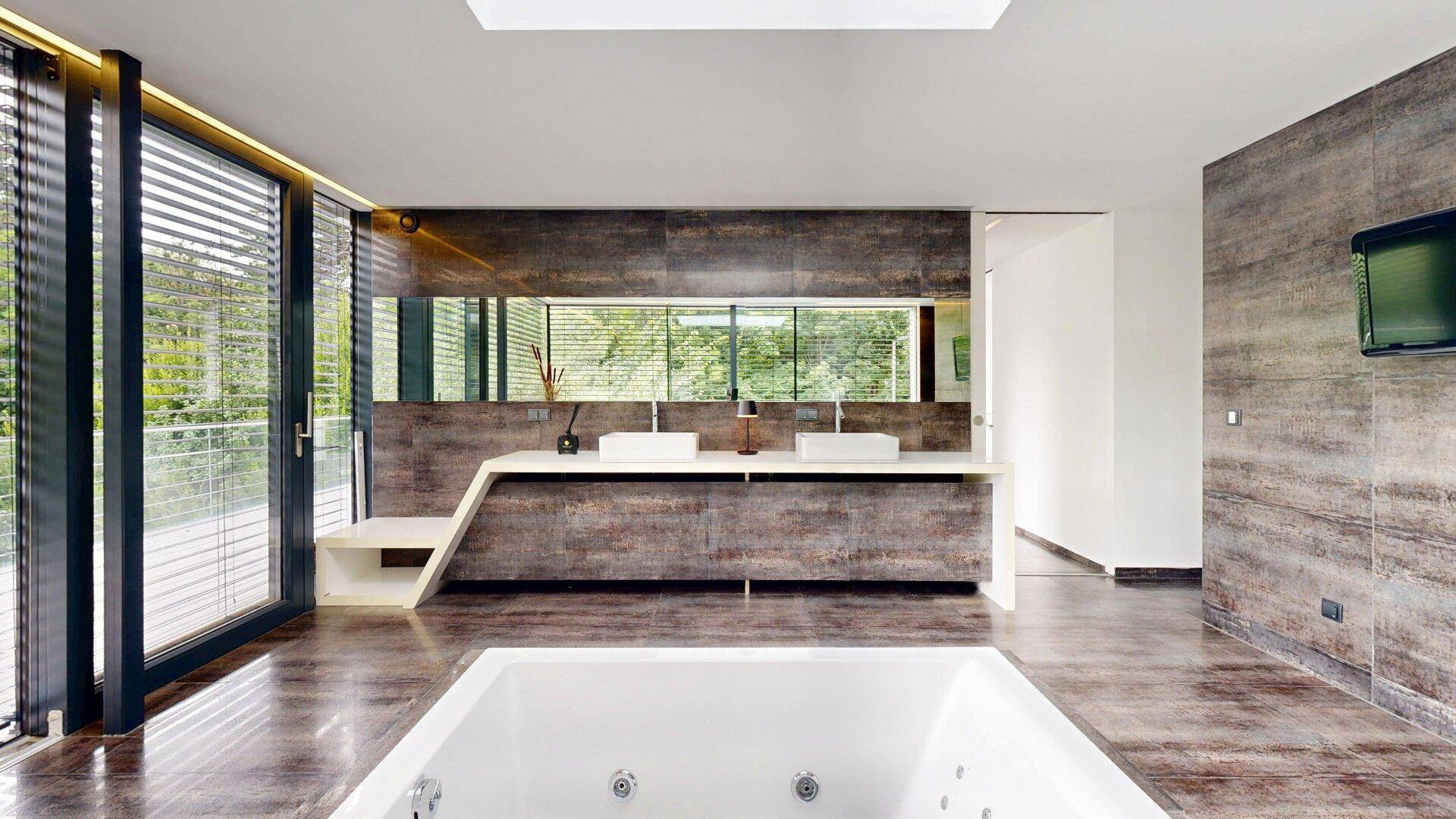 Geräumiges Badezimmer mit moderner Badewanne, Doppelwaschbecken und großen Schiebetüren zur Terrasse.