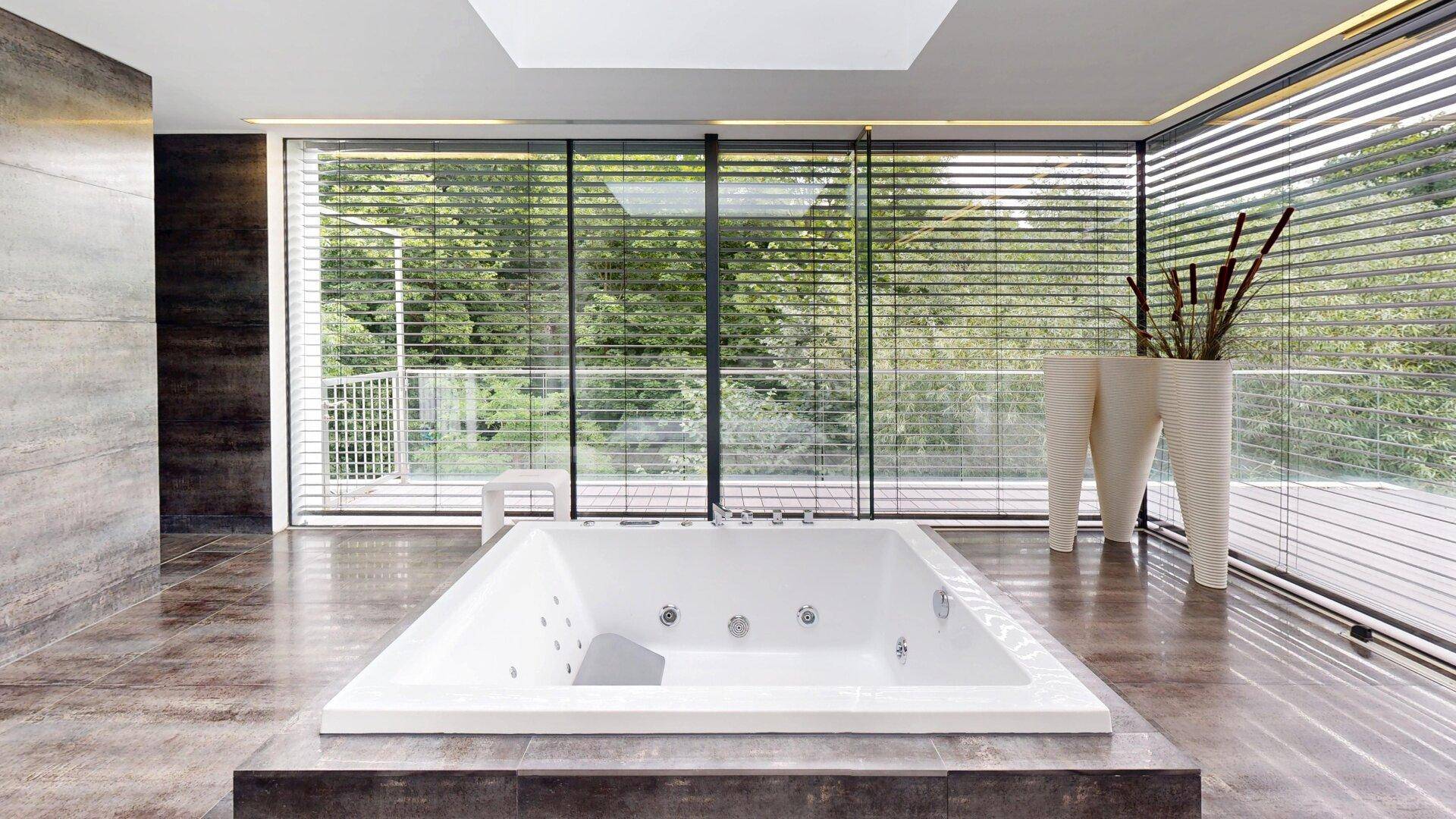 Helles Badezimmer mit Whirlpool-Badewanne und raumhohen Fenstern, die einen weiten Blick bieten.