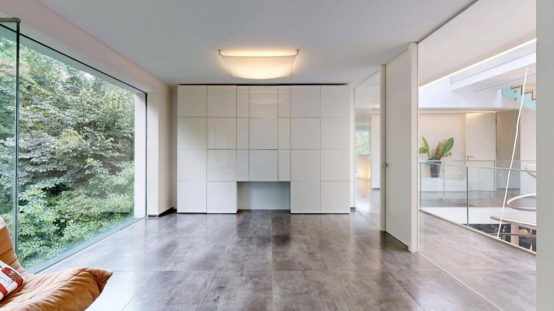 Geräumiges Wohnzimmer mit großen Fenstern und Blick auf den modernen Flurbereich.
