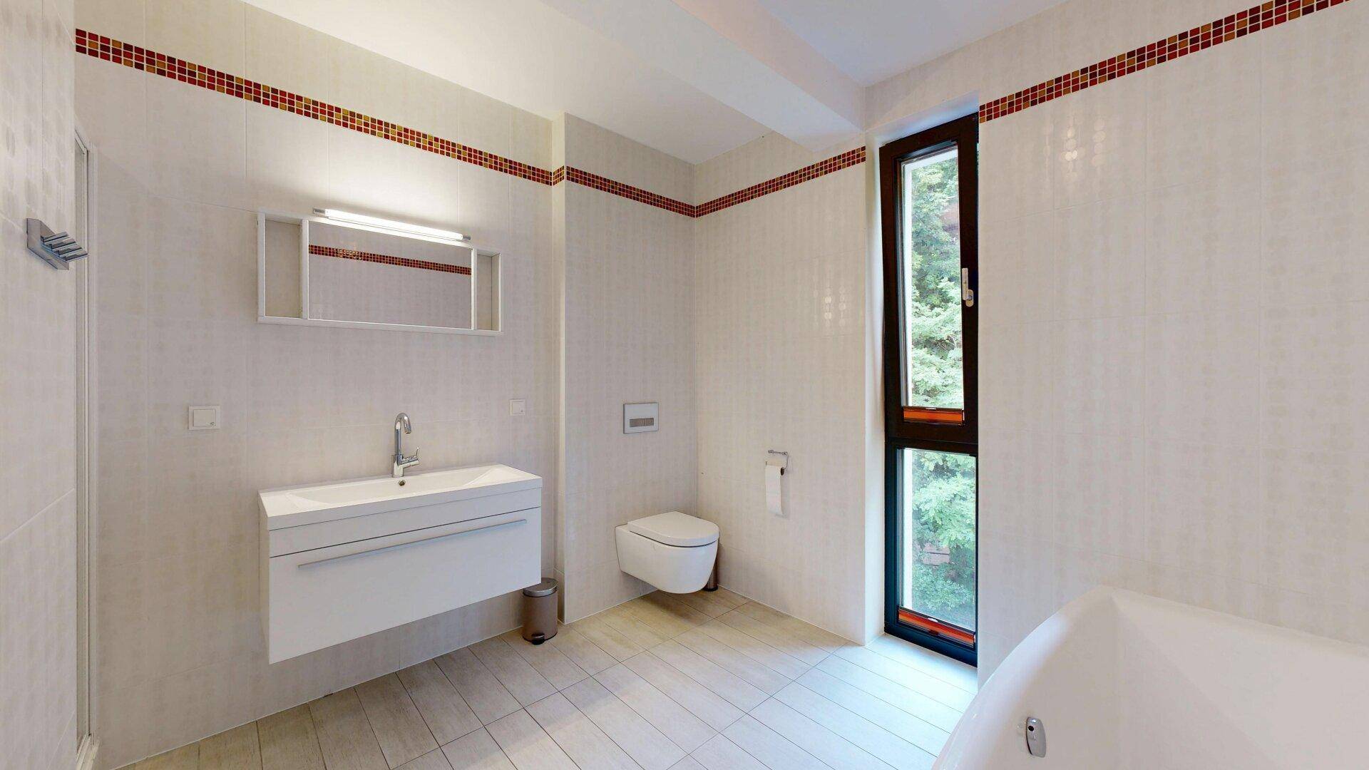 Helles Badezimmer mit Badewanne, wandhängendem WC, modernem Waschtisch und Fenster.