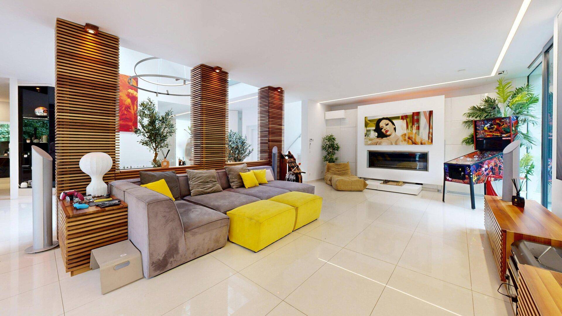 Geräumiges Wohnzimmer mit modernem Sofa, Kamin und dekorativen Holzelementen.
