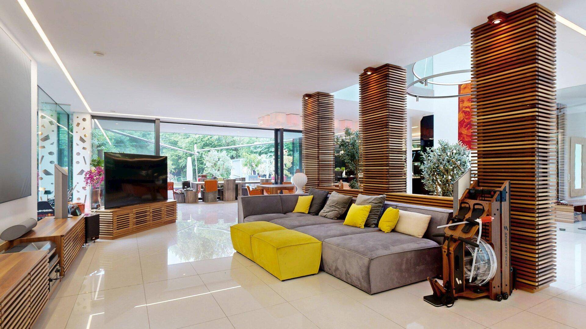 Heller Wohn- und Essbereich mit modernem Sofa, Holzelementen und großen Fenstern.