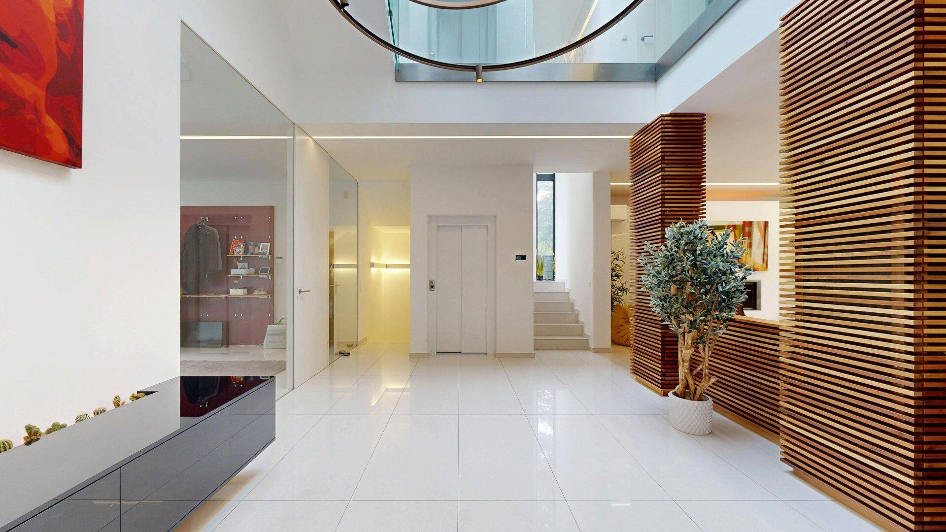 Heller Eingangsbereich mit Aufzug, Treppe und modernen Designelementen.