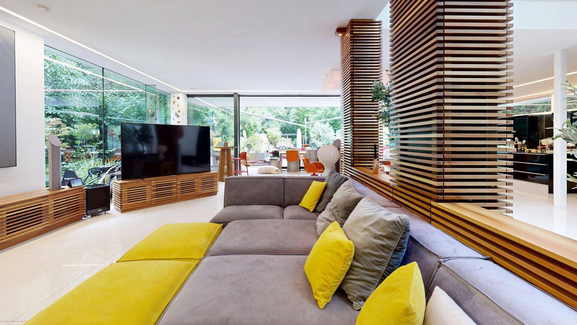 Offener Wohnbereich mit großem Sofa, Holzelementen und Übergang zum Essbereich.