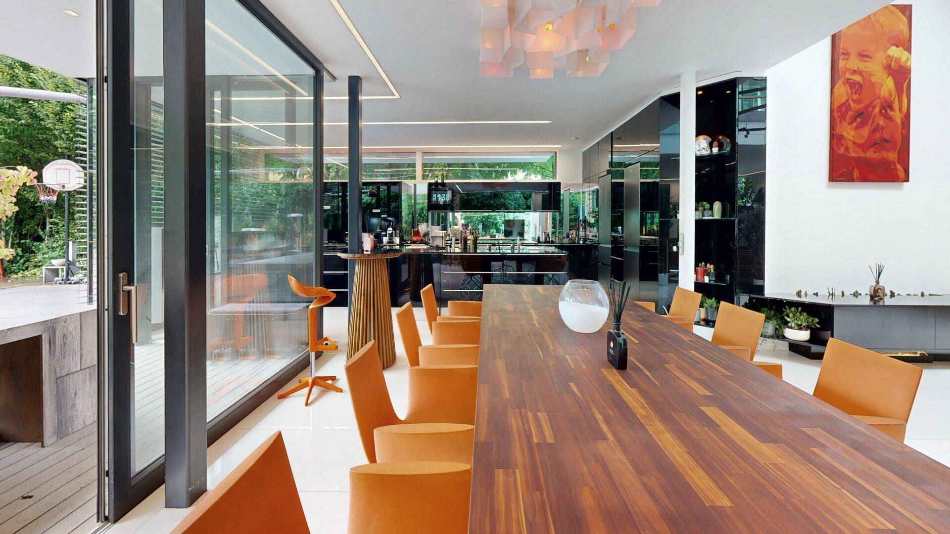 Geräumiger offener Wohn- und Essbereich mit Holztisch, modernen Stühlen und Zugang zur Terrasse.