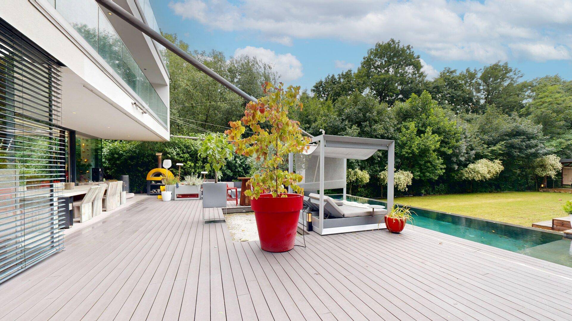 Exklusive Terrasse mit Pool, Sonnenliegen und Blick auf den weitläufigen Garten.