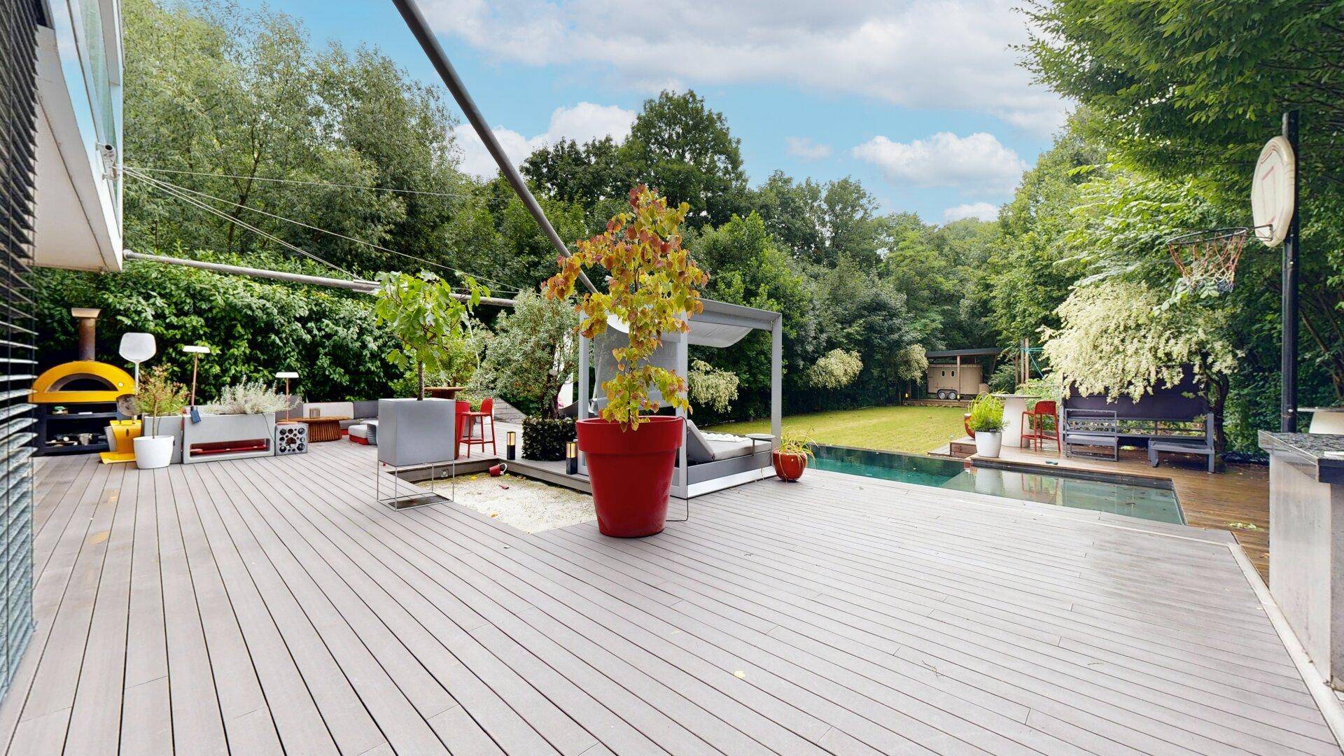 Großzügige Terrasse mit Swimmingpool, Liegebereich und üppiger Gartenlandschaft.