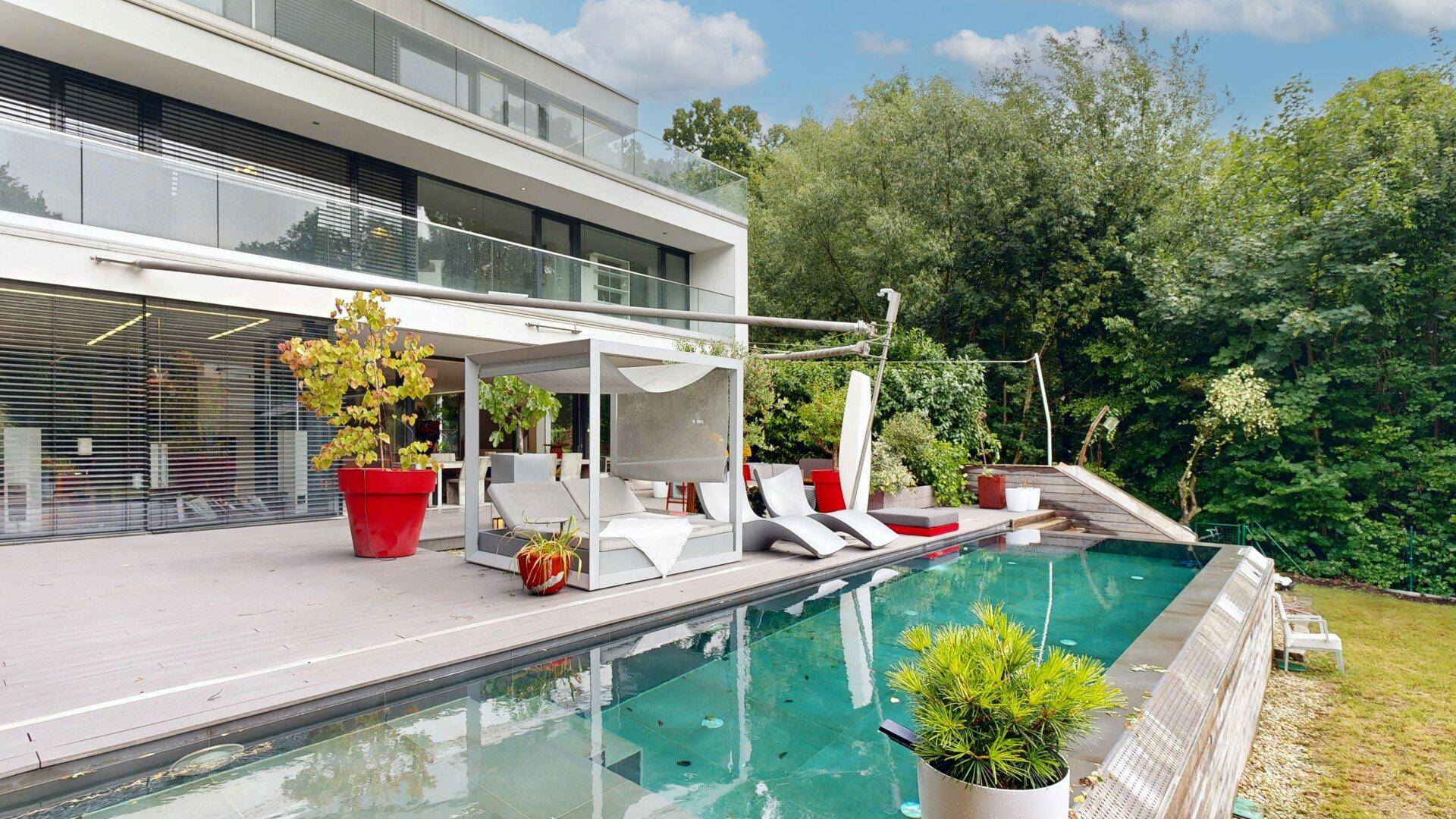 Moderne Terrasse mit Pool und luxuriösem Liegebereich vor der Hausfassade.