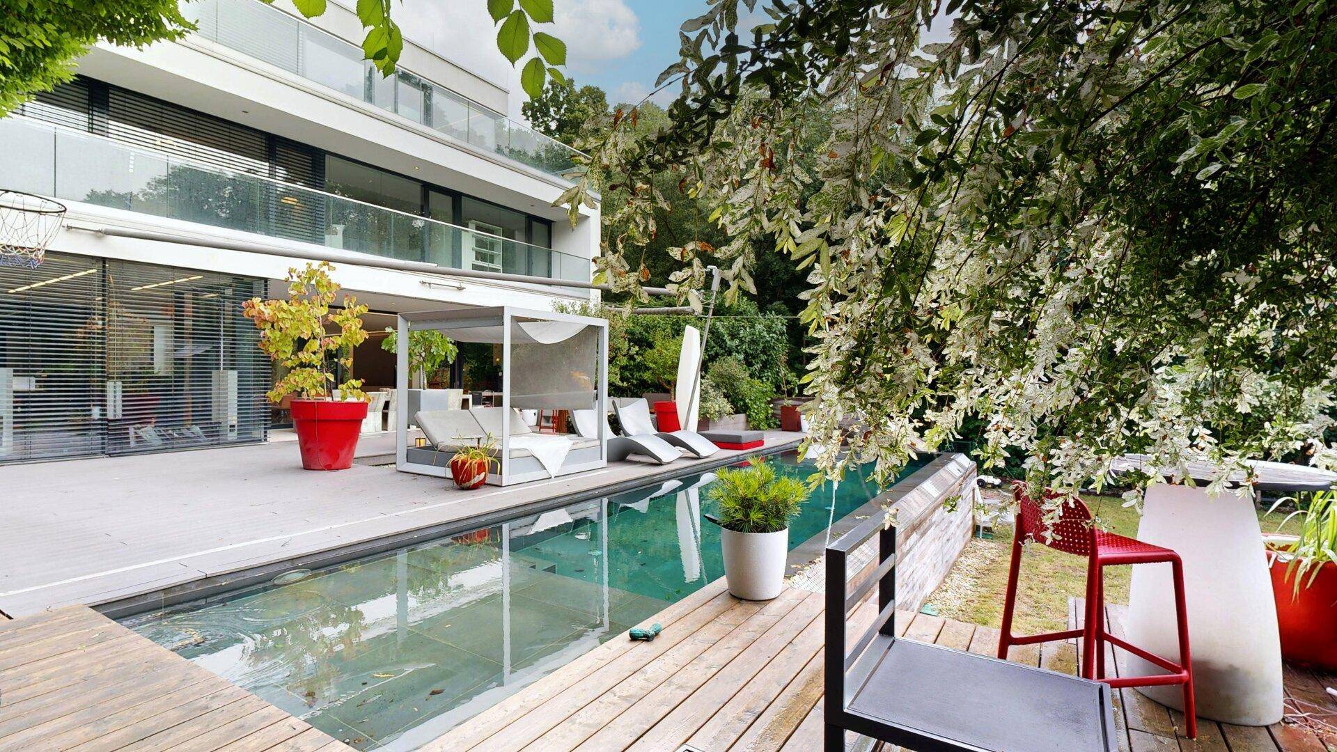 Attraktive Terrasse mit Pool, Holzdeck und üppiger Vegetation im Garten.