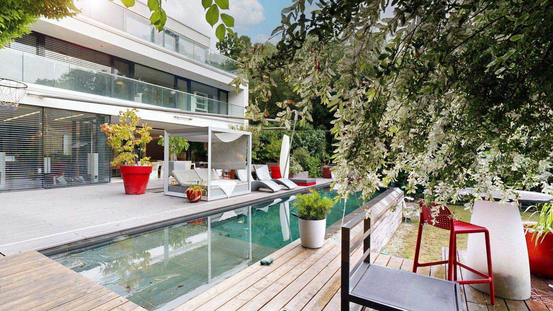 Großzügige Terrasse mit Pool, Holzdeck und grüner Umgebung, ideal zum Entspannen.