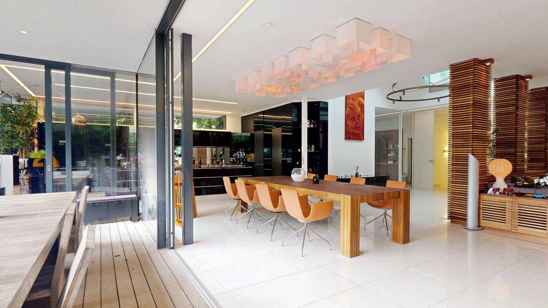 Heller Essbereich mit modernem Holztisch und orangefarbenen Stühlen, mit Terrassenzugang.