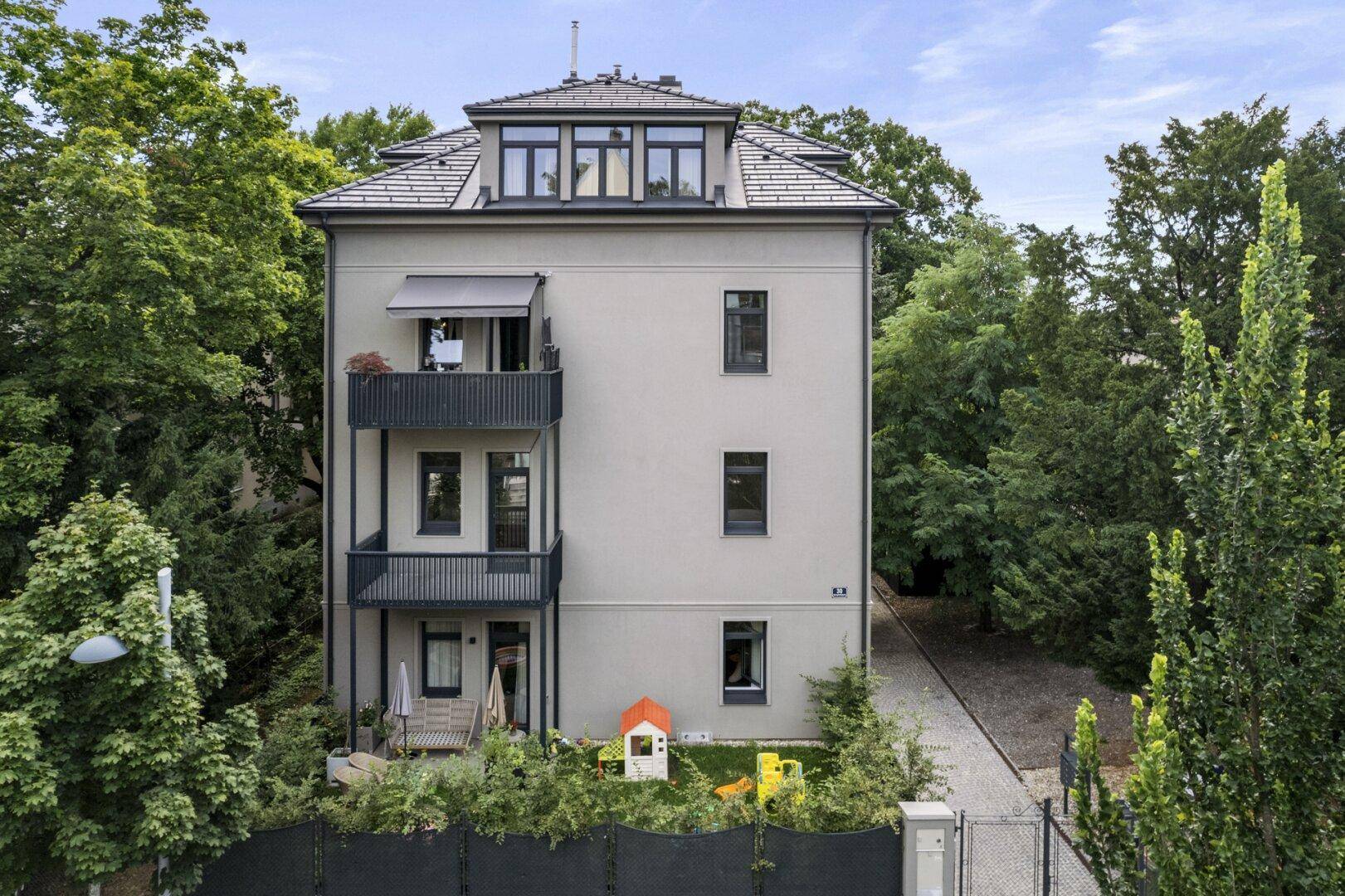 Detailansicht der Gebäudefassade mit Balkonen und einem kleinen, kinderfreundlichen Bereich im Freien.