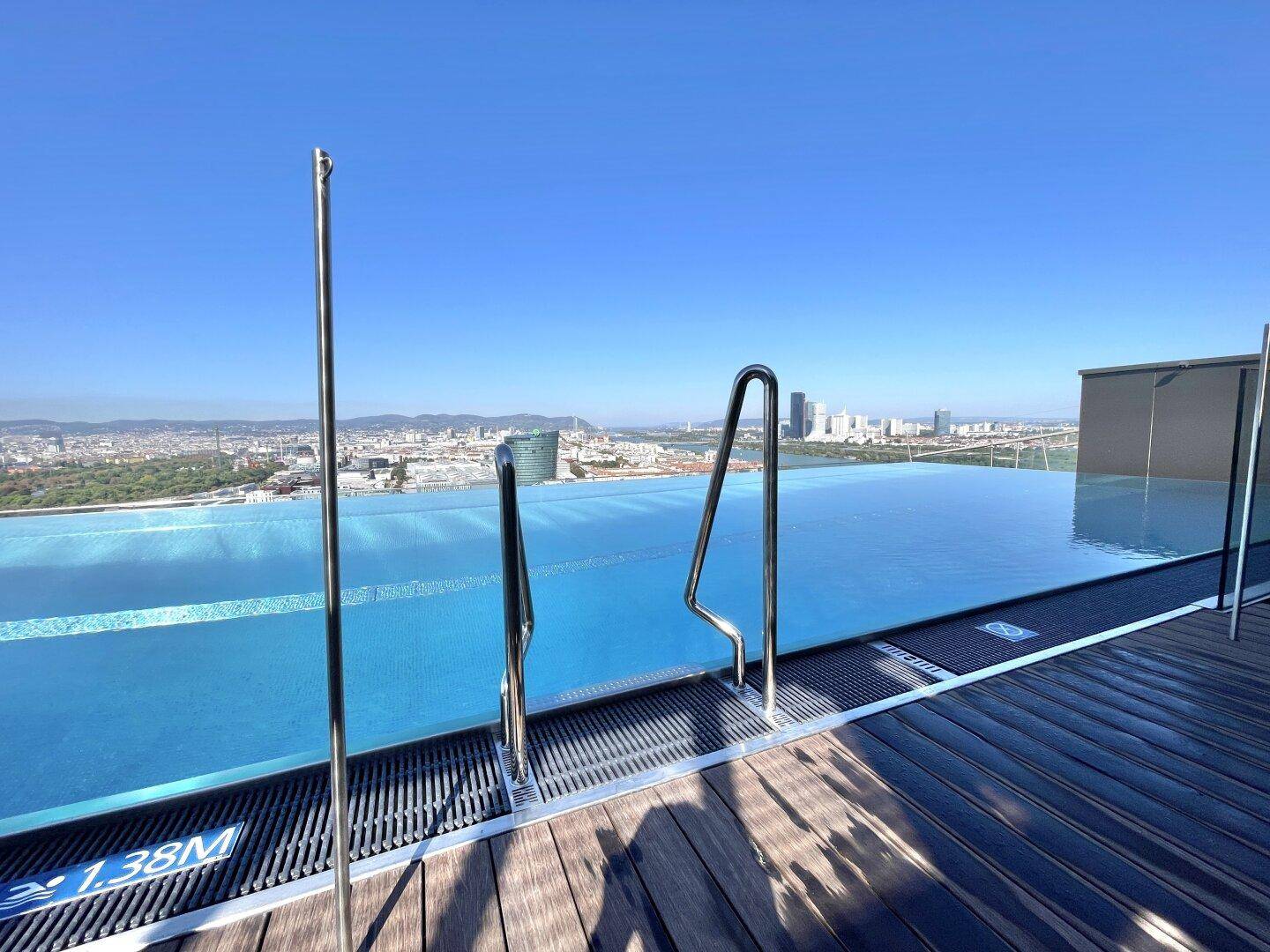 Atemberaubender Infinity-Pool auf dem Dach mit weitem Stadtblick und klarem blauem Himmel.