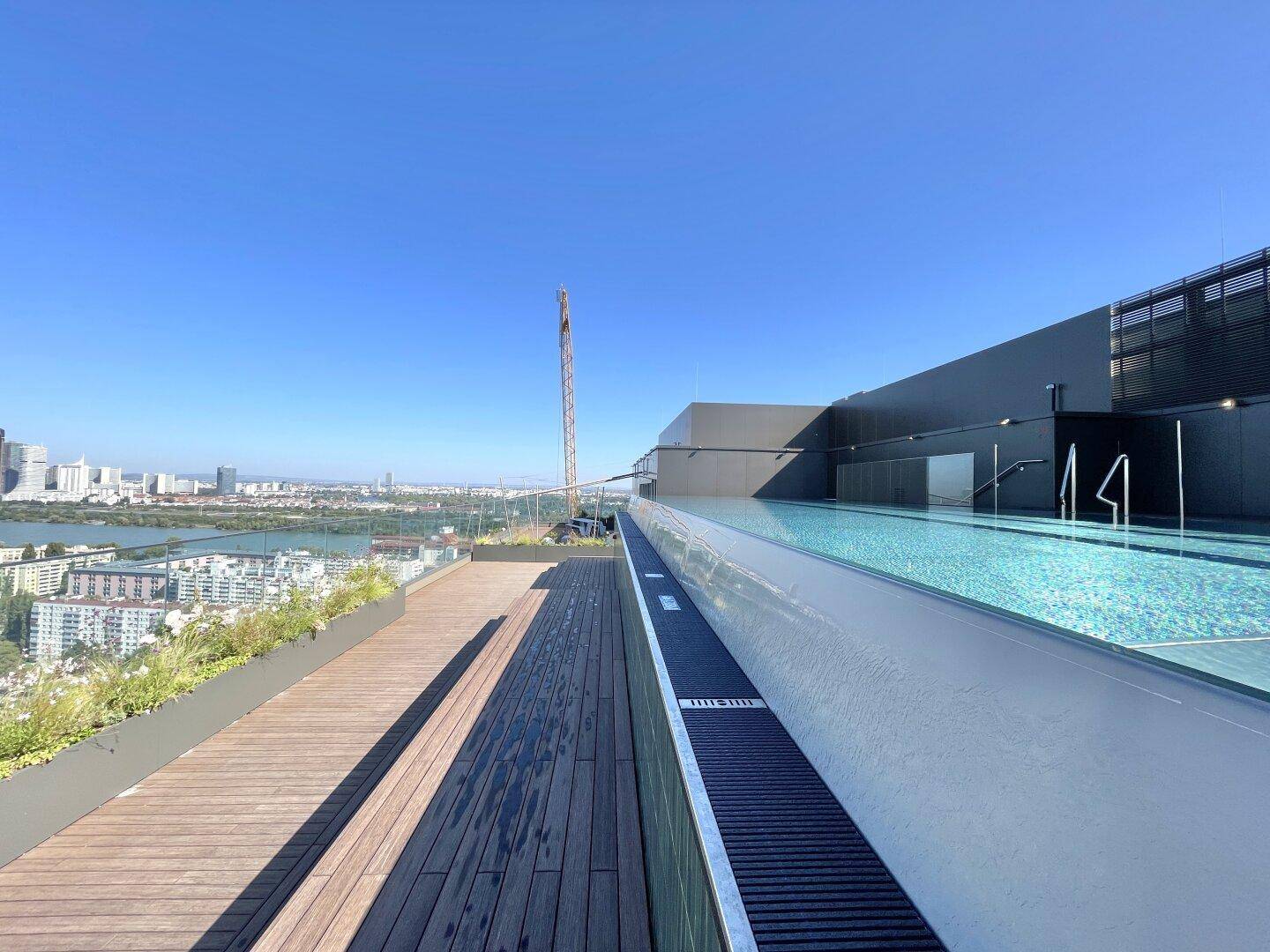 Holzdeck neben dem Infinity-Pool auf dem Dach mit Blick auf die Stadt und die Skyline.