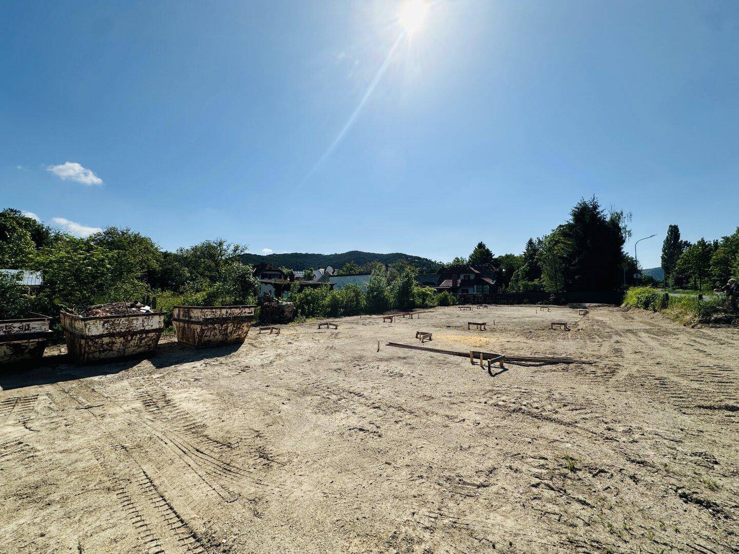 Weitläufiges Baugrundstück mit Baucontainern und Blick auf die umliegende Landschaft.