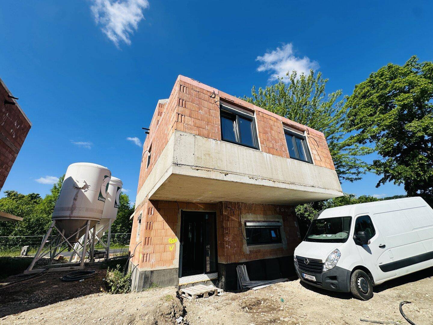 Nahaufnahme des im Bau befindlichen Gebäudes mit installierten Fenstern und einem Lieferwagen.