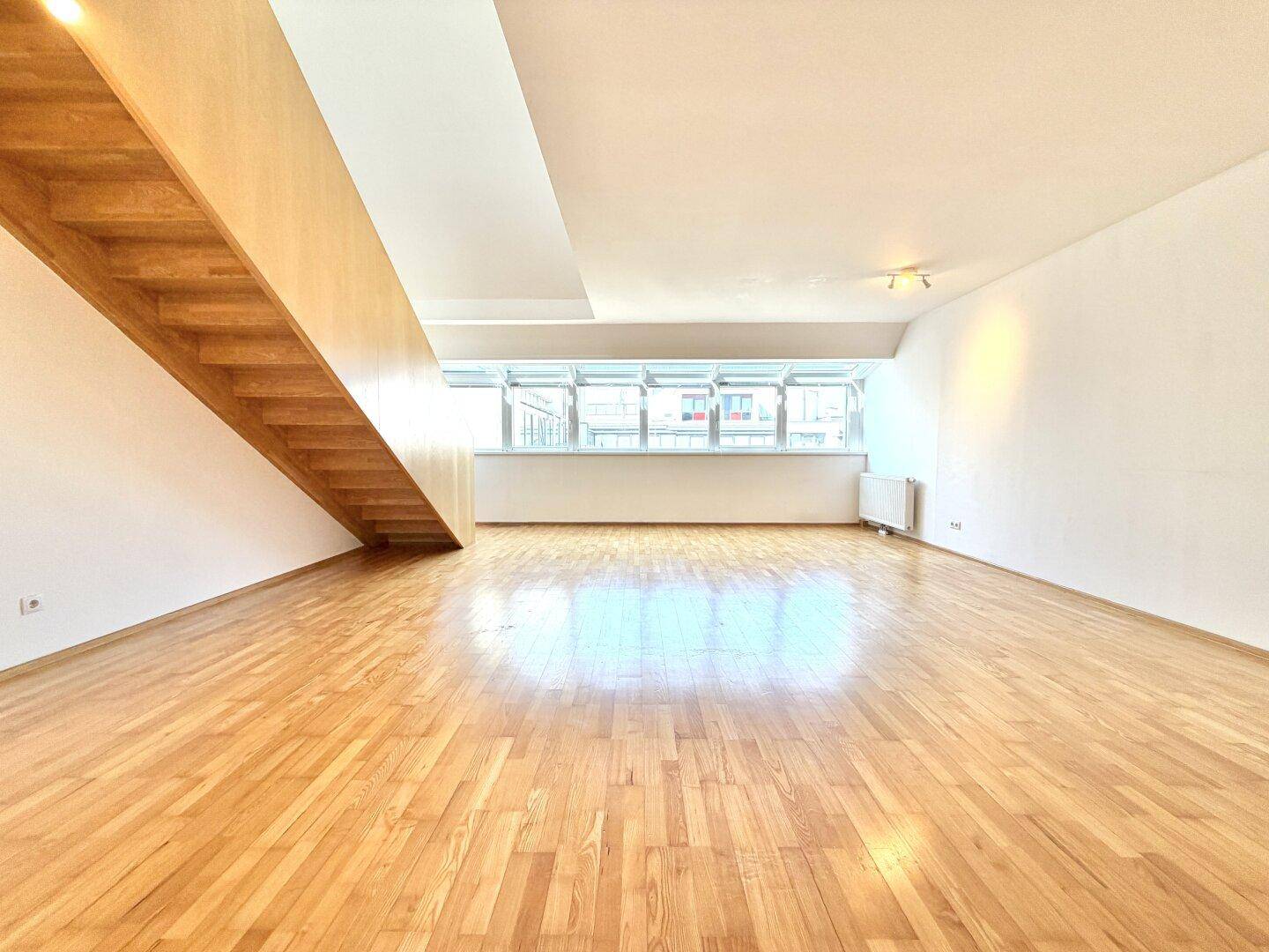 Helles, geräumiges Wohnzimmer mit Holzparkettboden und großer Fensterfront.