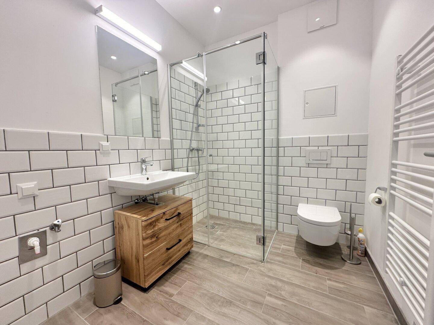 Modernes Badezimmer mit begehbarer Dusche, Holzwaschtisch und weißen Metrofliesen.