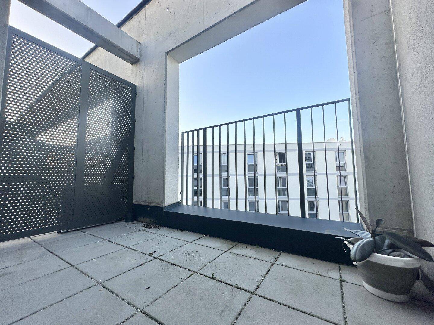 Moderner Balkon mit Metallgeländer und Blick auf umliegende Gebäude.