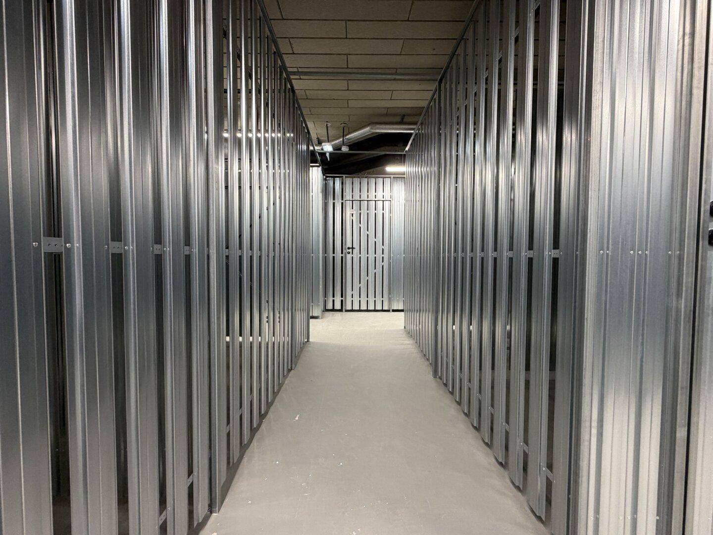 Langer Kellergang mit individuellen Abteilen aus Metall, ideal für zusätzlichen Stauraum.