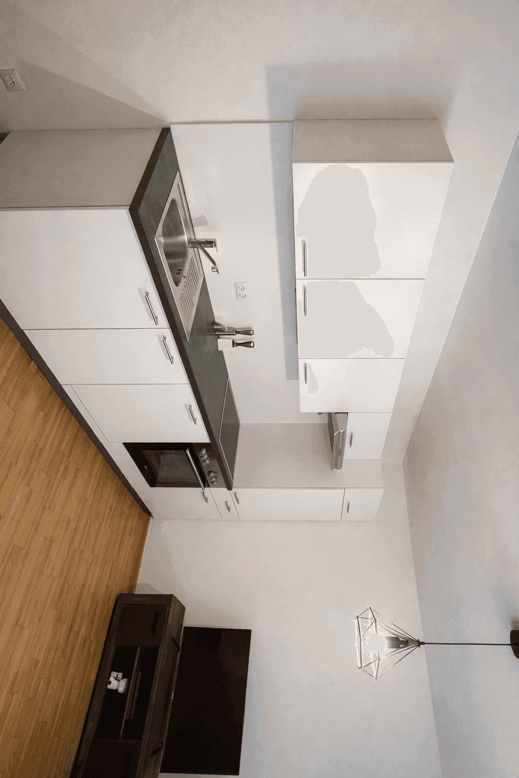 Moderne Küche mit weißen Schränken, dunkler Arbeitsplatte und Holzboden.