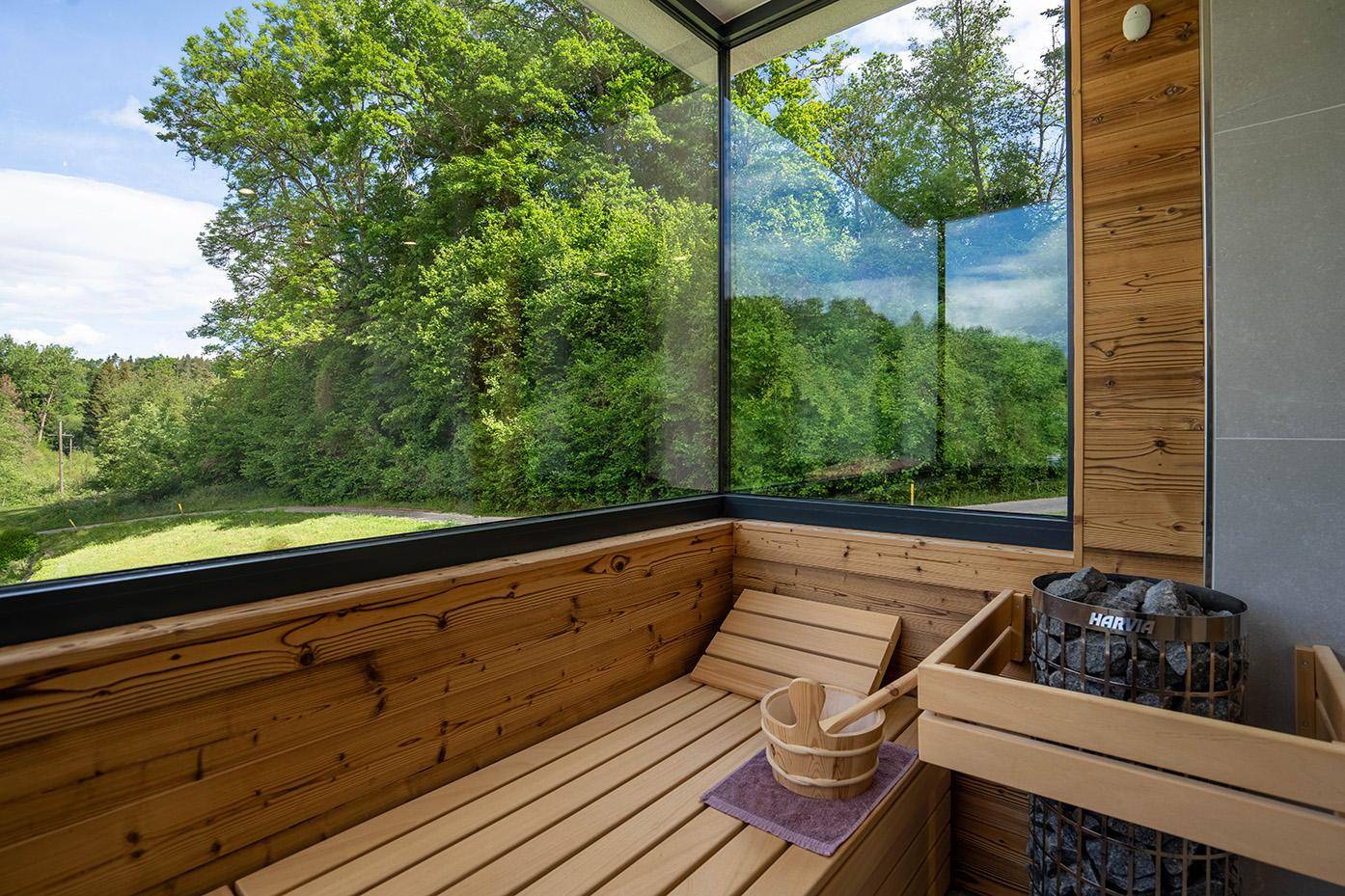 Moderne Sauna mit Holzverkleidung und großen Glasflächen für einen entspannenden Blick ins Grüne.