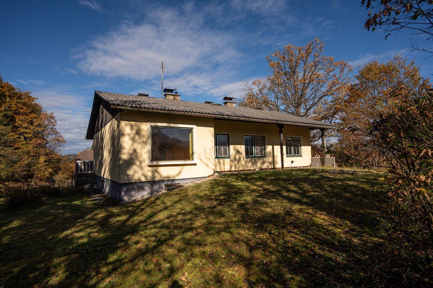 Rückansicht des Hauses auf einem Hanggrundstück mit weitem Blick und herbstlicher Vegetation.