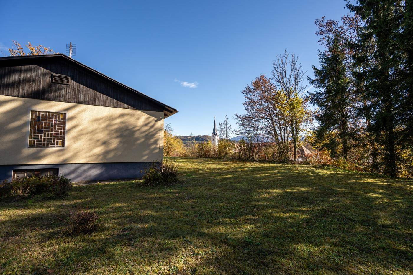Weitläufiger Gartenbereich hinter dem Haus mit Rasenfläche und Blick auf die umliegende Natur.