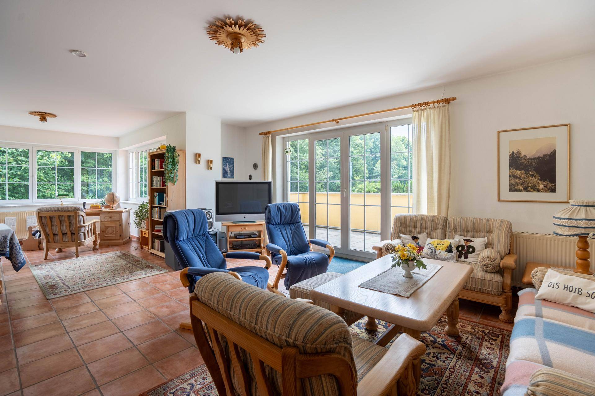 Heller Wohn- und Essbereich mit Terracottaboden und Zugang zur Terrasse, umgeben von Grün.