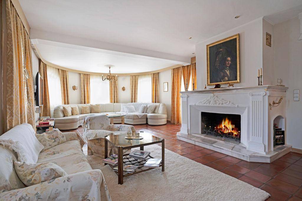 Helles Wohnzimmer mit opulentem Kamin, bequemen Sofas und großen Fenstern.