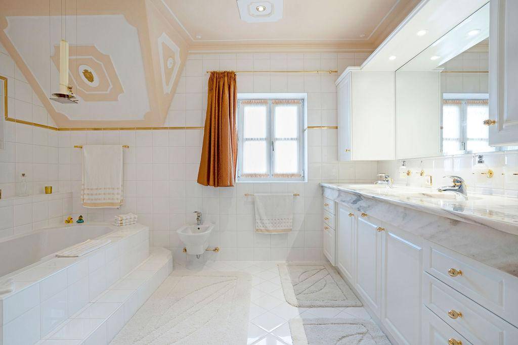 Geräumiges Badezimmer mit Marmorwaschtisch, Badewanne, Bidet und Fenster.