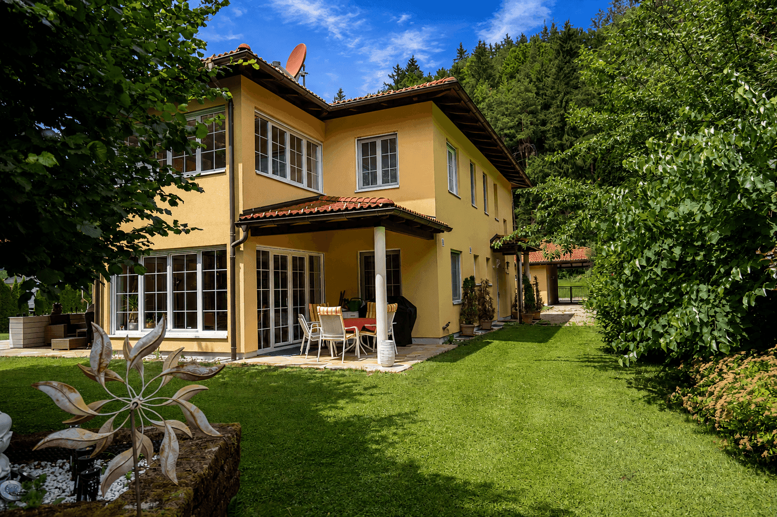 Überdachte Terrasse mit Gartenmöbeln und direktem Zugang zum weitläufigen Gartenbereich.