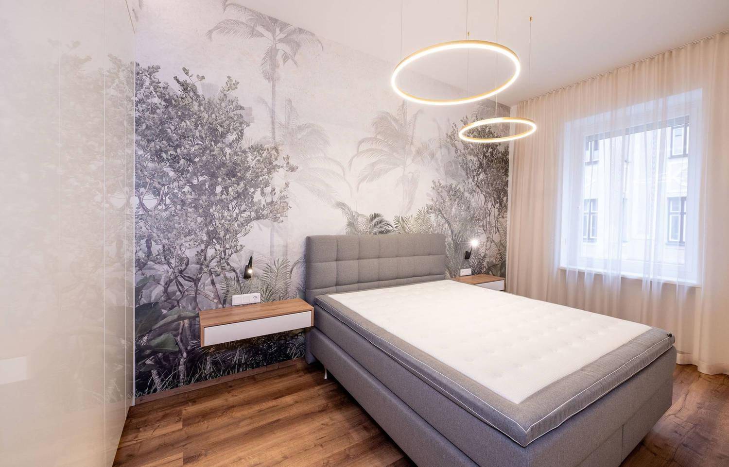 Elegantes Schlafzimmer mit großem Bett, Holzboden und dekorativer Tapete.