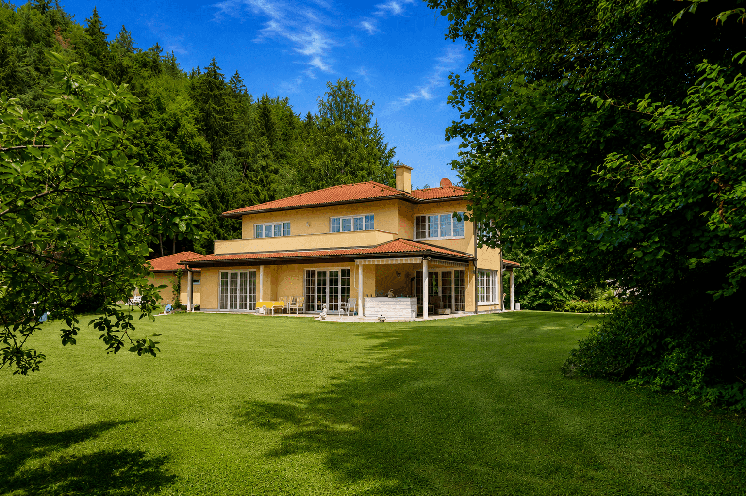 Weitläufiger Gartenbereich mit gepflegtem Rasen und Blick auf das charmante Wohnhaus.